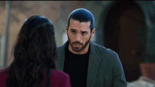 a man with a beard is talking to a woman in a red shirt