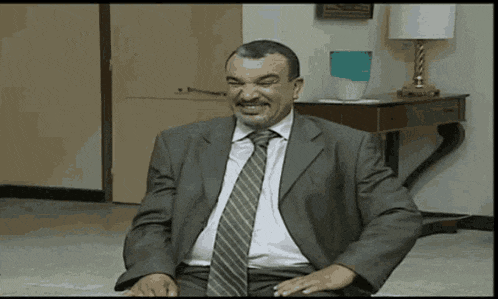 a man in a suit and tie is smiling while sitting on a chair