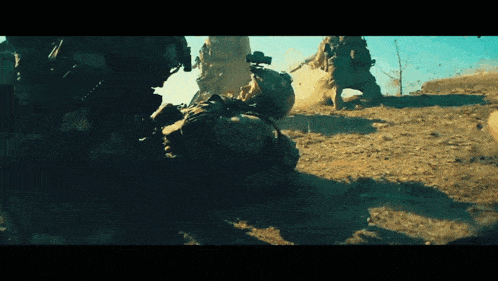 a group of soldiers are fighting in the dirt and one of them is laying on the ground
