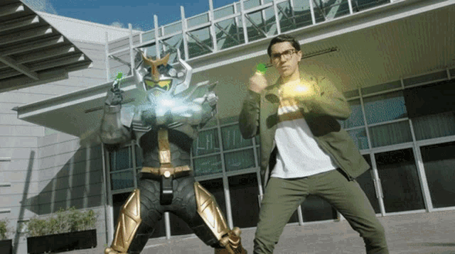 a man in a white shirt stands next to a robot in a black and gold suit