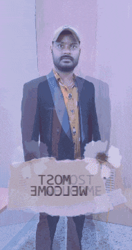a man in a suit and hat holds a cardboard sign that says most welcome