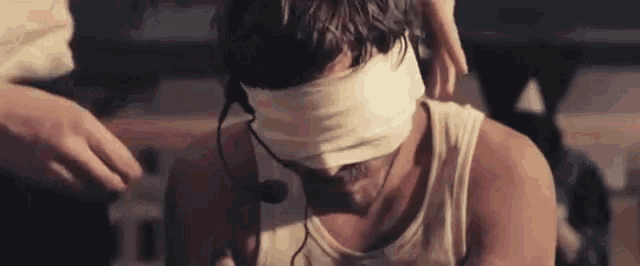 a man is blindfolded and wearing headphones while sitting down .