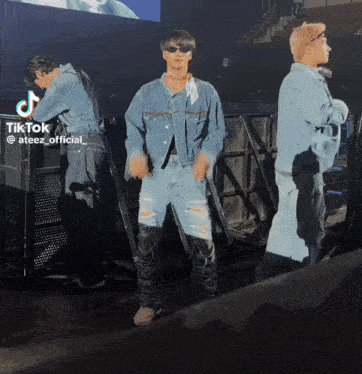 a man in a denim jacket is dancing in front of a crowd