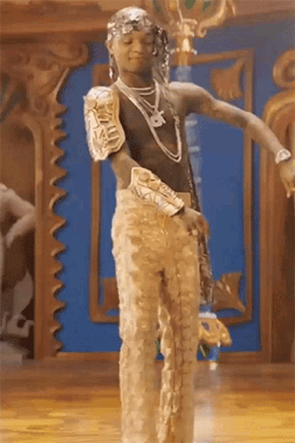 a man in gold pants and a black top is dancing