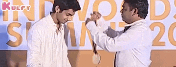 two men are shaking hands in front of a sign that says ' awards ' on it .