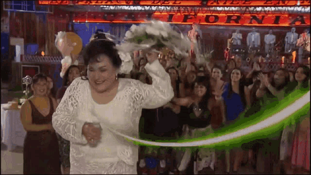 a woman in a white dress holds a bouquet of flowers in front of a sign that says california