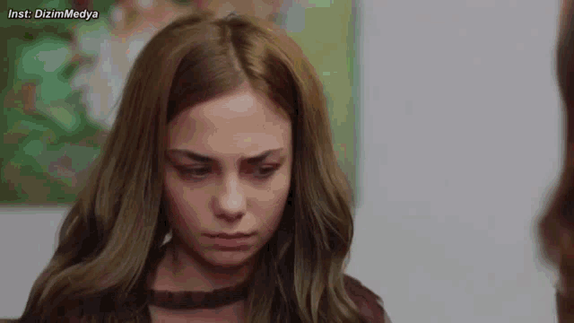 a close up of a woman 's face with a painting in the background .
