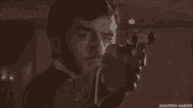 a man is pointing a gun at the camera .