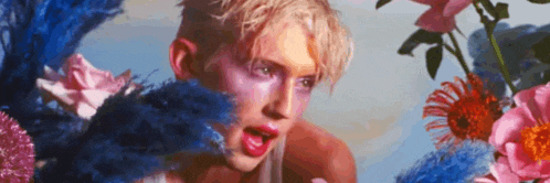 a man is surrounded by flowers with his mouth open