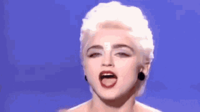 a woman with blonde hair and red lipstick is making a peace sign with her fingers .