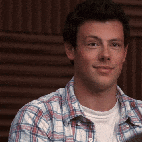 a man wearing a plaid shirt and a white shirt is smiling
