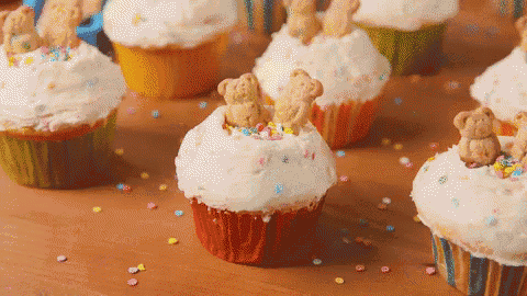 a bunch of cupcakes with teddy bears on top and sprinkles