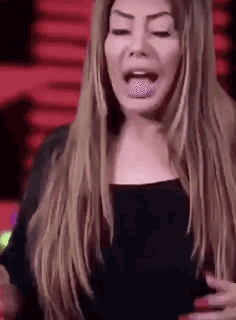 a woman with long hair is making a funny face and sticking out her tongue .