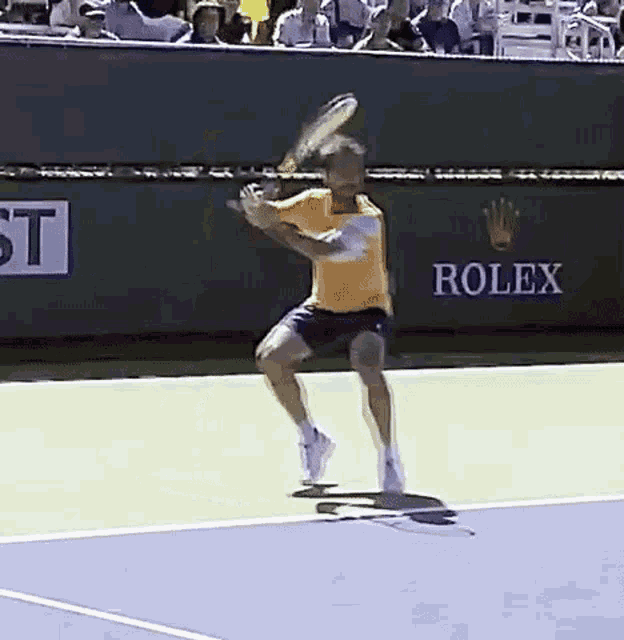 a man is swinging a tennis racket on a tennis court with a rolex sign in the background