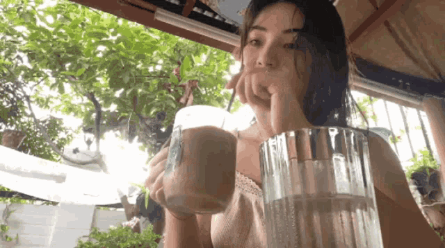 a woman sitting at a table with a glass of water and a glass of milkshake