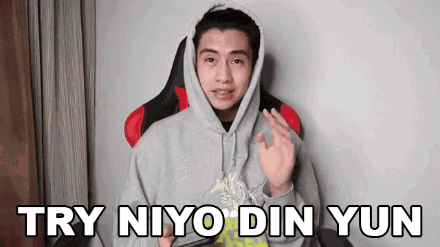 a man in a hoodie is sitting in a chair holding a cell phone and says `` try niyo din yun '' .