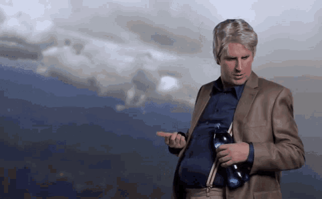 a man in a suit holds a bottle of coca cola in front of a cloudy sky