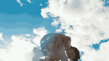 a person is laying on their back in front of a cloudy blue sky .