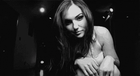 a black and white photo of a woman sitting on the floor in a room .