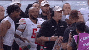 a football player with the number 5 on his jersey is talking to a coach