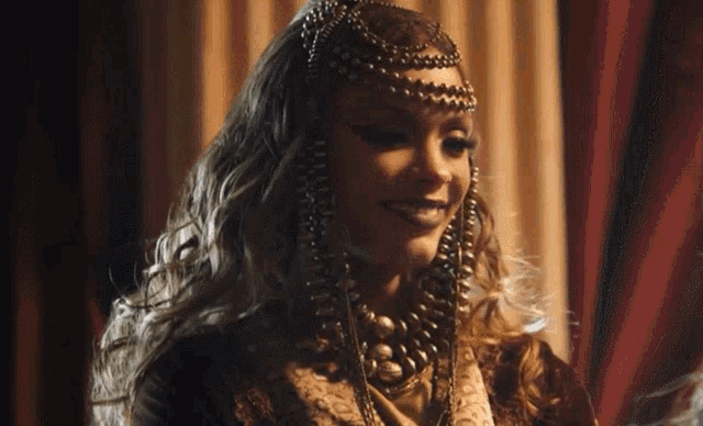 a woman wearing a necklace and a headpiece smiles