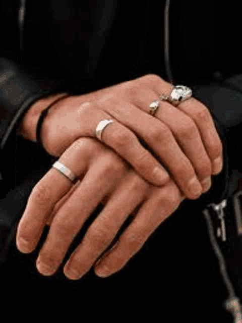 a person is wearing a lot of rings on their hands .