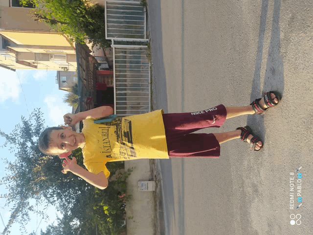 a boy wearing a yellow shirt that says istanbul is standing on the street
