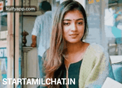 a woman with long hair is sitting in front of a sign that says starttamilchat in