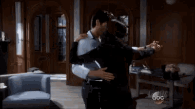 a man and a woman are dancing in a living room with a chair .