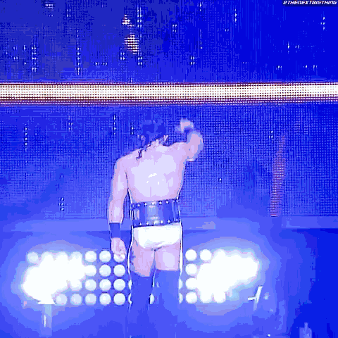 a wrestler is standing in front of a screen that says the nextbigthing