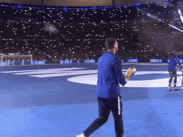 a man in a blue jacket is holding a trophy in front of a crowd