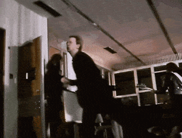 a man in a suit is standing in a room with a woman