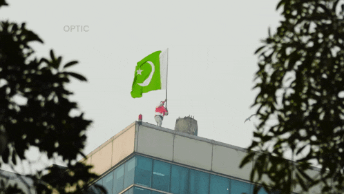 a green flag is flying on top of a building with optic written on the bottom