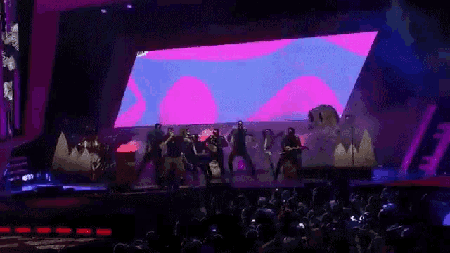 a man playing a guitar on a stage in front of a large screen