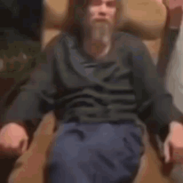 a man is sitting in a chair with his legs crossed and a bottle of beer in his hand .