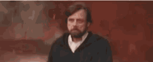 a man with a beard is holding a gun in his hand .