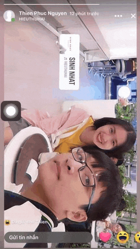 a man and a woman are sitting next to each other with a sign that says sinh nhat on it