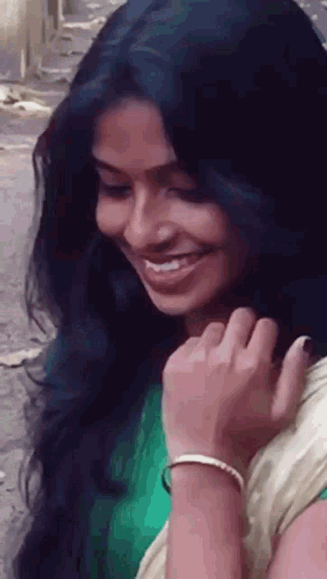 a woman with long black hair is smiling and holding her hair