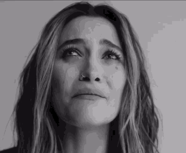 a woman with a nose ring is crying with a tear coming out of her eye