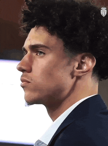 a man with curly hair is wearing a blue suit