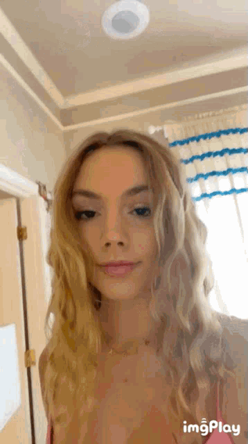a woman is taking a selfie in a room with a ceiling light .