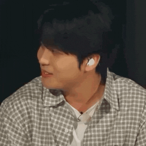 a man in a plaid shirt is making a funny face while wearing headphones .