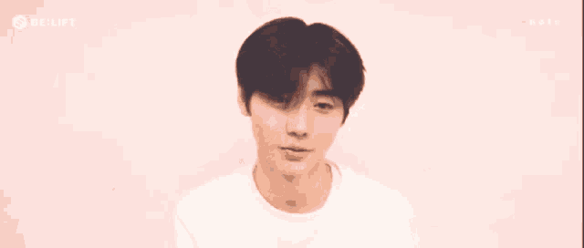 a young man in a white shirt stands in front of a pink background with the word relift on it