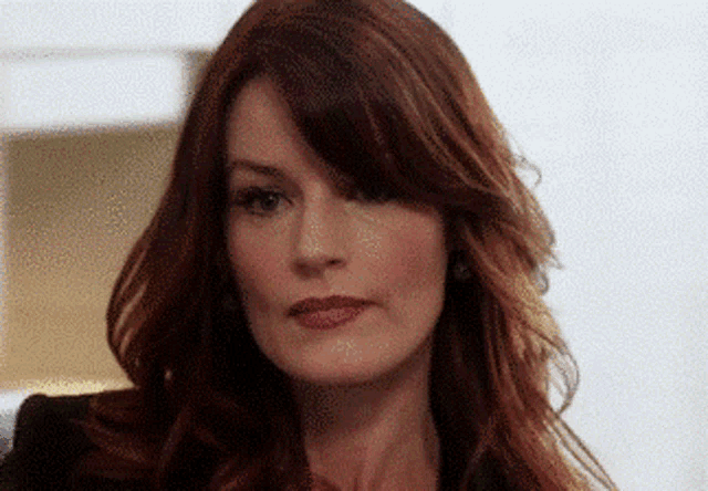 a close up of a woman 's face with red hair and red lips