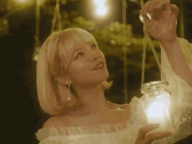 a woman in a white dress is holding a lantern in her hands .