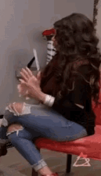 a woman is sitting on a red chair clapping her hands