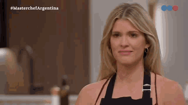 a woman in an apron is crying in a kitchen