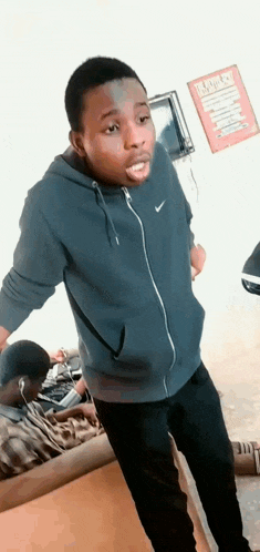a man wearing a nike hoodie is standing in front of a sign that says ' i love you '