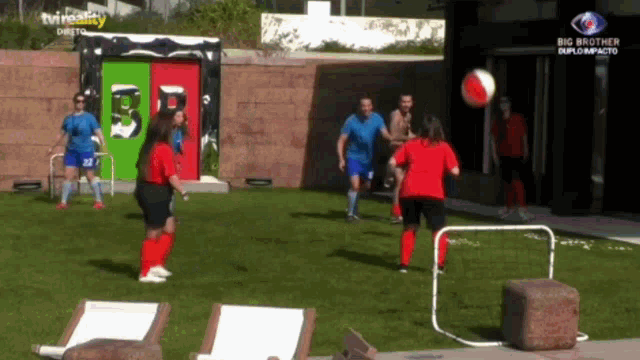 a group of people are playing soccer in front of a building that has the word big brother on it