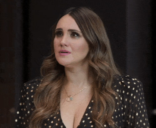 a woman wearing a black and gold polka dot dress has a gold necklace around her neck